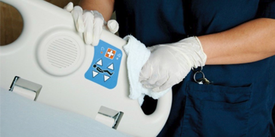 worker wearing medical gloves cleaning hospital equipment